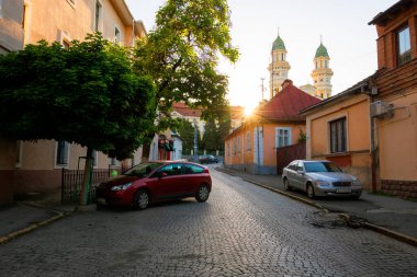 Uzhorod, Ukrayna - Haziran 04, 2017: Eski Avrupa şehrinin boş caddesi gün doğumunda. Güneş, Yunan Katolik katedralinin arkasında. popüler seyahat hedefi