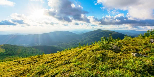 Yaz akşamları harika bir dağ manzarası. Büyük dağ sıralarının yuvarlanan tepeleri ılık ışıkta mavi gökyüzündeki tüylü bulutların altında