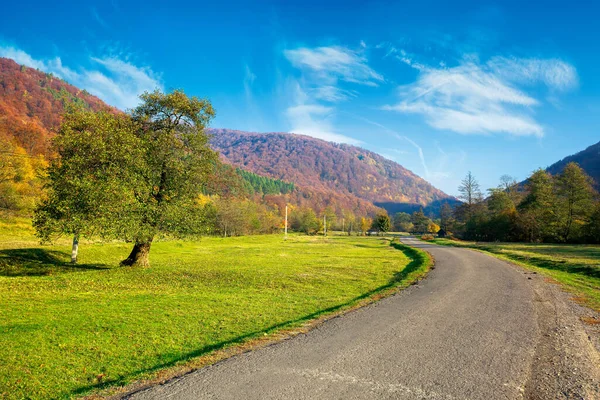 乡间小路蜿蜒穿过山谷 美丽的秋天山景 多彩的树叶覆盖在山丘上的森林 阳光灿烂 天空中乌云密布 — 图库照片