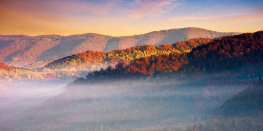 Sonbaharda dağ manzarası. Sis sabah ışığında parlıyordu. Gün doğumunda bulutlu dramatik gökyüzü