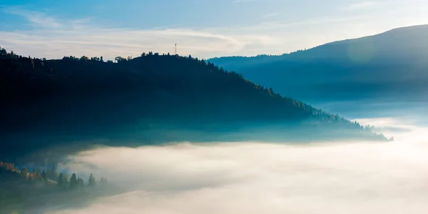 idyllic autumn landscape with cold morning fog on hillside in mountainous rural area at sunrise