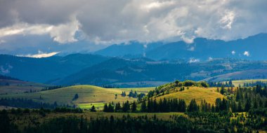Dağlık kırların güzel manzarası. Tepelerin üstündeki bulutlar uzak vadiye doğru yuvarlanıyor. Noktalı ışıkta karpatya manzarası. dramatik hava koşulları. 