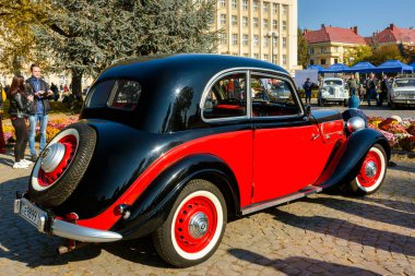 Uzhhorod, Ukrayna - 31 Ekim 2021: siyah bluzlu kırmızı bmw 321 'in arka görüntüsü. 40 'lı yılların klasiği. Bagajında maskot olan yedek tekerlek. Sonbaharda Narodna Meydanı 'nda klasik araç sergisi