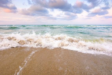 Fırtınadan önce deniz gelgiti. Islak kumsalda köpüklü dalgalar. Kadife mevsiminde rüzgarlı bir hava. dramatik deniz manzarası arkaplanı