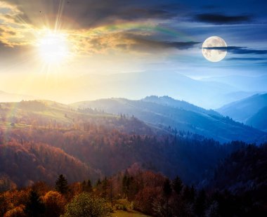 Güzel dağ manzarası. Gündüz ve gece zaman kavramını değiştirir. Sonbahar ekinoksunda harika bir kır manzarası. Kırsal otlaklar ve ağaçlar renkli yapraklar içinde yuvarlanan tepelerde güneş ve ay ile