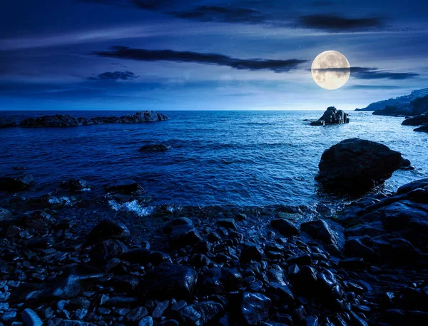 Geceleri çakıl taşı kıyısı. Güzel yaz tatili mevsimi dolunay ışığında denizde.