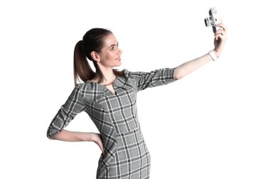 Beyaz arka plan üzerinde izole retro vintage fotoğraf makinesinde çekim alarak selfie yapıyor içinde gülümseyen genç kadın.