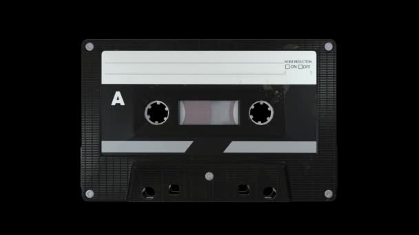 Cinta de casete de audio vintage que se reproduce sobre un fondo negro — Vídeo de stock