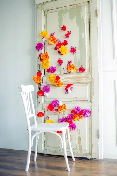 white wooden chair on the background of a door decorated with colorful flowers
