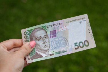 bir arka plan bulanık çim alanı metin için beş yüz hryvnas. Bir banknot tutmak el