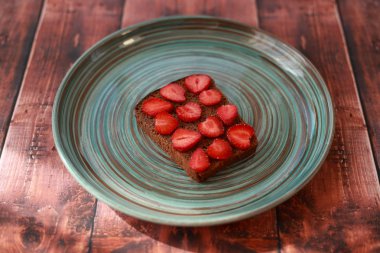 çilek dilimlenmiş çavdar ekmeği bir tabak ve ahşap bir masa