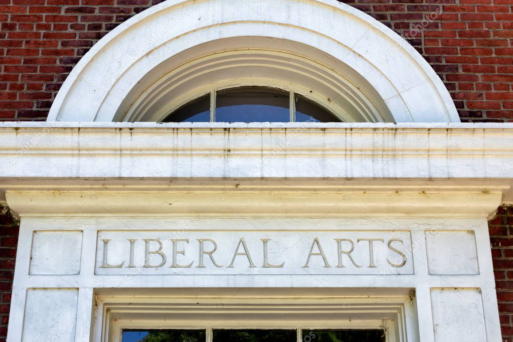 Worn and weathered liberal arts lettering on brick wall.