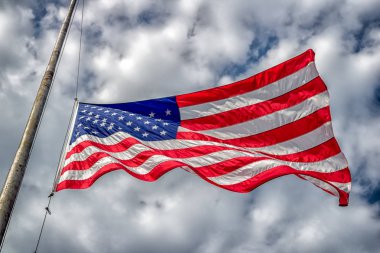 Amerikan bayrağı yarıya veya mavi gökyüzü ve bulutlar ile rüzgarda üfleme half-staff.
