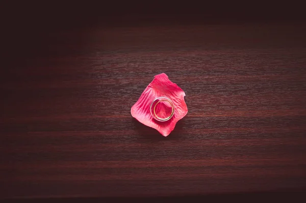 Alyans koyu ahşap yüzey üzerinde pembe bir yaprağı üzerinde