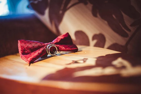 Wedding rings and red bow tie on a stringed instrument close-up