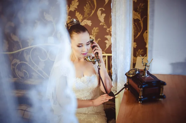 Beyaz elbise ve retro telefon yakın çekim ile uzun duvak gelin