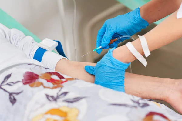 Nurse inserts needle into vein for drip infusion in hospital