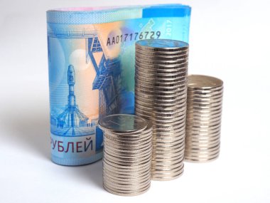 2000 rublelik Rus banknotlarının bir demet beyaz bir kağıt arka plan üzerinde duruyor. Önünde bozuk para yığınları var. Banknotlar Vostochny uzay limanını ve Soyuz roketini gösteriyor.