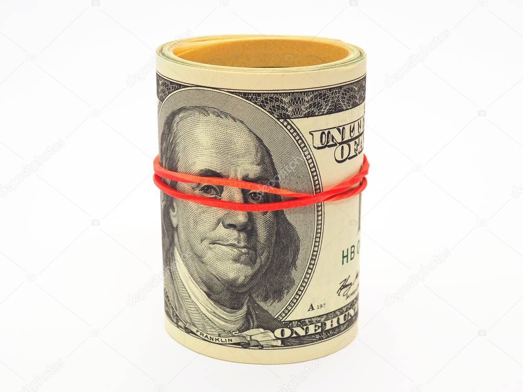 A bundle of old-style 100 dollar bills stands on a white paper background. Banknotes are rolled up and pulled together with a rubber band. Not isolated. A gum passing through Franklin's face looks like a mask. Off books money. Close-up
