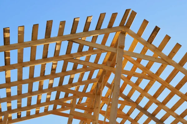 青い空に対して黄色の木製の垂木 住宅の建設と修理のトピックに明るい背景 住宅の屋根の建設 — ストック写真