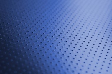 Endüstriyel mavi arka plan ve parlak doymuş renk. Birçok deliği olan delinmiş alüminyum yüzey. Safları uzaklaşıyor ve bir perspektif oluşturuyor. Koyu metal duvar kağıdı. Makro