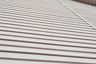 Plastik kaplamanın çizgili yüzeyi ve bir parça korniş. Binaların yapımı ve onarımı. Açık kahverengi ya da bej arkaplan ya da duvar kağıdı. Malzeme ve teknoloji üretimi