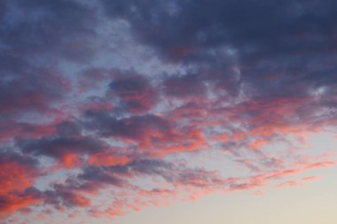 Gün batımında gökyüzü. Mavi ve kırmızı doğal arka plan veya duvar kağıdı. Batan güneşin ışınları bulutları etkin bir şekilde aydınlatır. Güzel akşam gökyüzü. Hava tahminleri