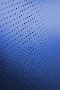 Parlak doymuş renklerle boyanmış mavi metal arka plan. Koyu dikey duvar kağıdı. Birçok deliği olan delinmiş alüminyum yüzey. Safları uzaklaşıyor ve bir perspektif oluşturuyor. Makro