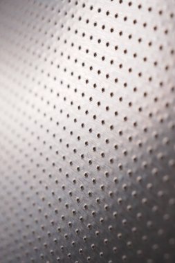 Birçok deliği olan delinmiş alüminyum yüzey. Safları uzaklaşıyor ve bir perspektif oluşturuyor. Koyu dikey duvar kağıdı. Endüstriyel gri metal arka plan. Makro