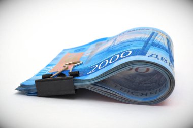 Rus parası. 2000 ruble 'lik banknotlar bir ofis şarjörüyle bağlanır ve beyaz bir yüzeye konur. Rusya 'da çocuk nafakası ve işsizlik yardımı. Makro