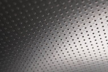 Koyu metalik duvar kağıdı ya da arka plan. Çok sayıda deliği olan delinmiş alüminyum yüzey, tavana asılmış gibi. Performans satırları mesafeye gider ve perspektif oluşturur