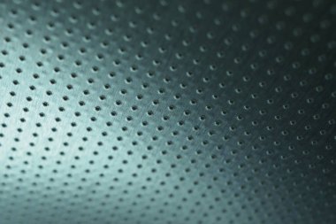 Koyu metalik duvar kağıdı. Renkli mavi ya da yeşil arka plan. Çok sayıda deliği olan delinmiş alüminyum yüzey, tavana asılmış gibi. Performans satırları mesafeye gider ve perspektif oluşturur