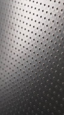 Koyu metalik cep telefonu duvar kağıdı. Birçok deliği olan delinmiş alüminyum yüzey. Soyut endüstriyel teknoloji geçmişi. Dikey metal arka plan. Makro
