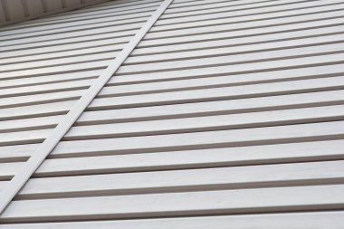 Çizgili plastik kaplama yüzeyi ve korniş parçası. İnşaat ve binaların tadilatı. Açık gri arkaplan veya masaüstü duvar kağıdı. İnşaat malzemeleri veya teknolojileri