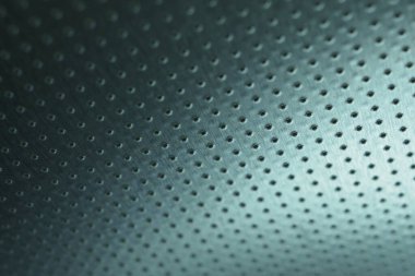 Koyu metalik duvar kağıdı. Renkli mavi-yeşil arka plan. Çok sayıda deliği olan delinmiş alüminyum yüzey, tavana asılmış gibi. Performans satırları mesafeye gider ve perspektif oluşturur