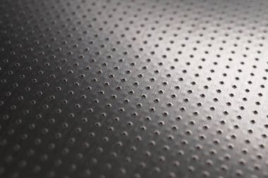 Endüstriyel metal. Siyah duvar kağıdı. Birçok deliği olan delinmiş alüminyum yüzey. Safları uzaklaşıyor ve bir perspektif oluşturuyor. Makro