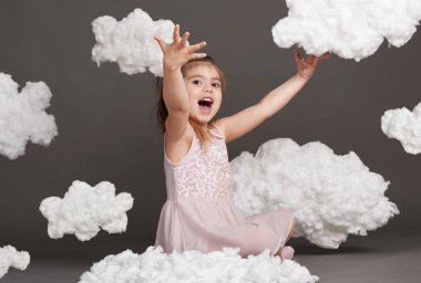 bulutlar, gri bir arka plan üzerinde stüdyoda çekim ile oynayan kız