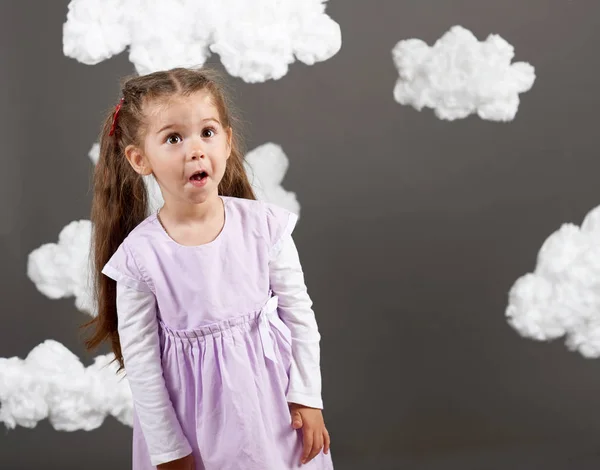 girl playing with clouds, shooting in the studio on a gray background, happy childhood concept