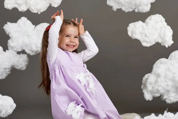 girl playing with clouds, shooting in the studio on a gray background, happy childhood concept