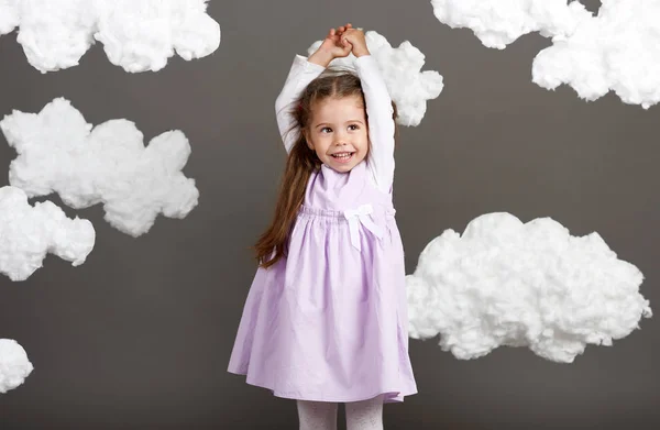 girl playing with clouds, shooting in the studio on a gray background, happy childhood concept