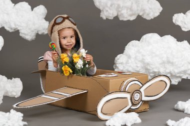 karton kutu ve bir pilot olma hayalleri bulutlar Pamuk yün gri bir arka plan üzerine yapılmış bir uçak kız çocuk oynar