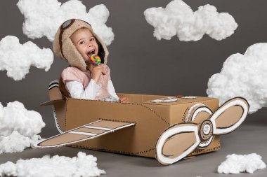 karton kutu ve bir pilot olma hayalleri bulutlar Pamuk yün gri bir arka plan üzerine yapılmış bir uçak kız çocuk oynar