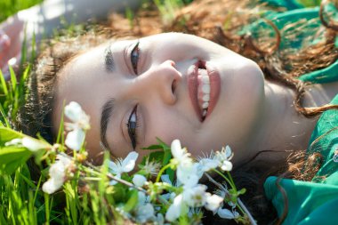 güzel kız çimlere güneşli gün, yüz closeup, yaz orman, parlak manzara gölgeler ile yalan