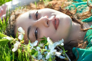 güzel kız çimlere güneşli gün, yüz closeup, yaz orman, parlak manzara gölgeler ile yalan