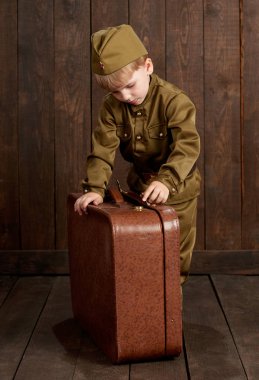 Çocuk Çocuk giymiş eski bavul, koyu ahşap arka plan, retro tarzı retro askeri üniformalı asker olarak
