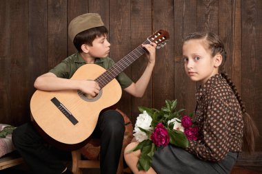 Çocuk bir asker gönderme ordu, koyu ahşap arka plan, retro tarzı oturma ve gitar, çalmak retro askeri üniforması giymiş