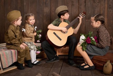 Çocuk bir asker gönderme ordu, koyu ahşap arka plan, retro tarzı oturma ve gitar, çalmak retro askeri üniforması giymiş