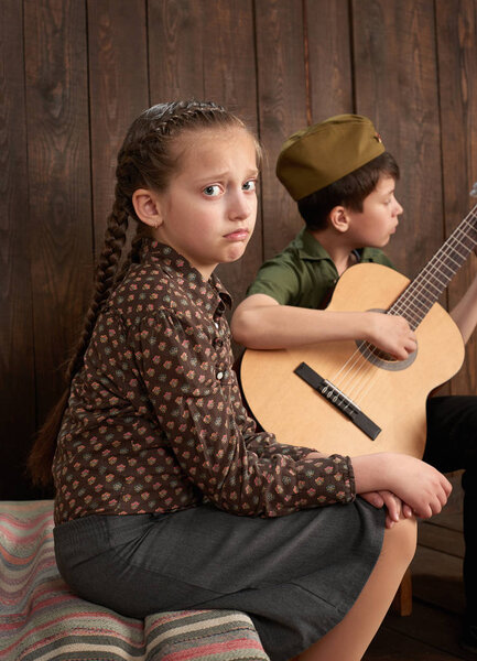 children are dressed in retro military uniforms sending a soldier to the army, dark wood background, retro style