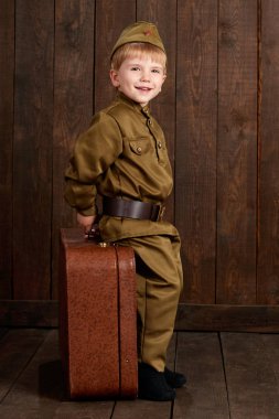 Çocuk Çocuk giymiş eski bavul, koyu ahşap arka plan, retro tarzı retro askeri üniformalı asker olarak