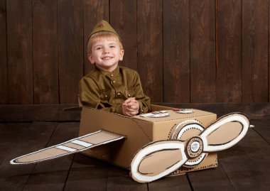 çocuk çocuk asker retro askeri üniformaları Sit karton kutu ve bir pilot, koyu ahşap arka plan, retro tarzı olma hayalleri yapılmış bir uçak olarak giyinmiş